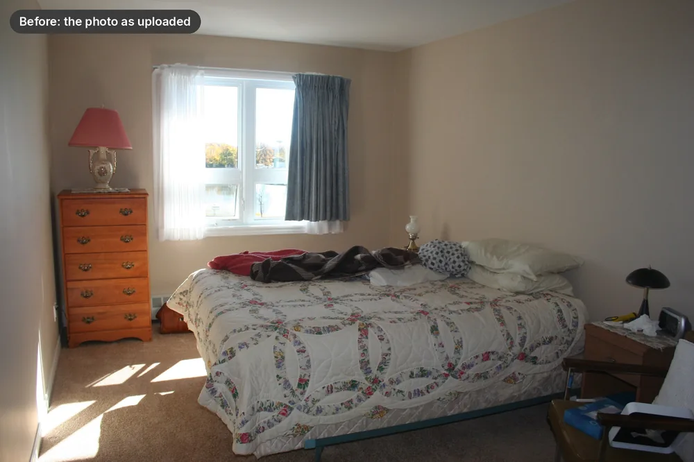 A real cluttered bedroom photo before staging: crowded nightstand, rumpled bedding, items on the floor